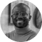An African American man smiling with glasses on.